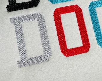 May include: Close-up of the word "DO" embroidered in silver, red, and blue thread on a white fabric background.
