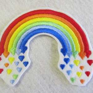 May include: A rainbow-colored embroidered patch with a white background. The rainbow is made up of red, orange, yellow, green, blue, and purple. There are small hearts of different colors falling from the rainbow.