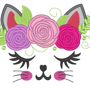 Può includere: Disegno ricamato di un viso di gatto con gli occhi chiusi, un naso a forma di cuore e baffi. Il gatto indossa una corona di rose rosa, viola e rosse con foglie verdi.