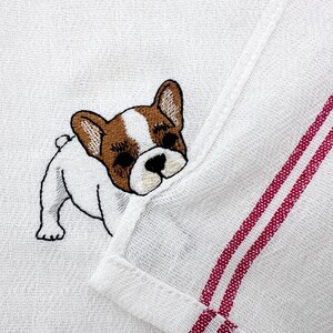 K&ouml;nnte beinhalten: Wei&szlig;es K&uuml;chentuch mit einem gestickten French Bulldog. Der Hund ist wei&szlig;, braun und schwarz. Das Handtuch hat zwei rote Streifen am Rand.