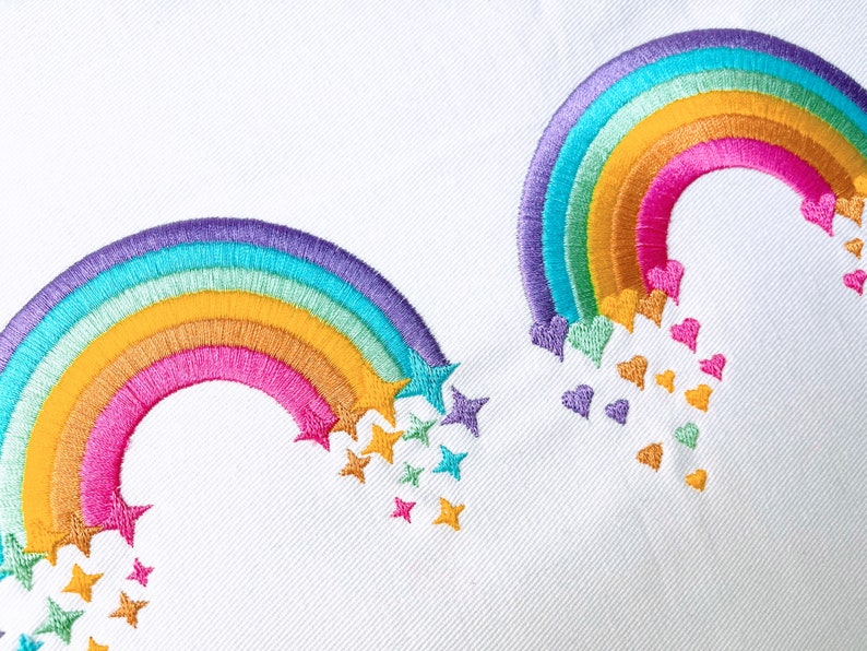 May include: Two embroidered rainbows with stars and hearts falling from them. The rainbows are purple, blue, green, yellow, pink, and orange. The stars are yellow, green, and blue. The hearts are purple, pink, and orange.