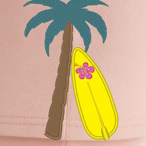 May include: Embroidered design featuring a palm tree with teal fronds and a brown trunk, leaning against a yellow surfboard. The surfboard has a pink and purple flower. The background is a light pink color.