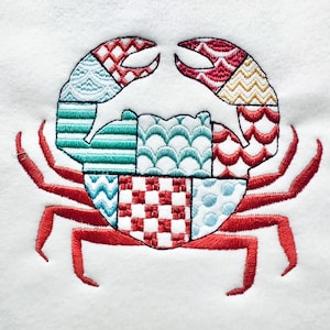 May include: Embroidered crab design with red legs and claws, and a body composed of various patterned segments in red, blue, and gold. The crab is set against a white background, showcasing the detailed stitching.