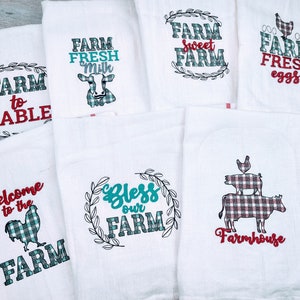 May include: Set of 7 white kitchen towels with red and teal checked designs and embroidered text. The text includes "Farm to Table", "Farm Fresh Milk", "Farm Sweet Farm", "Farm Fresh Eggs", "Welcome to the Farm", "Bless Our Farm", and "Farmhouse".
