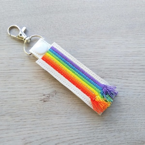 May include: White keychain with a rainbow embroidered design and a silver key ring.