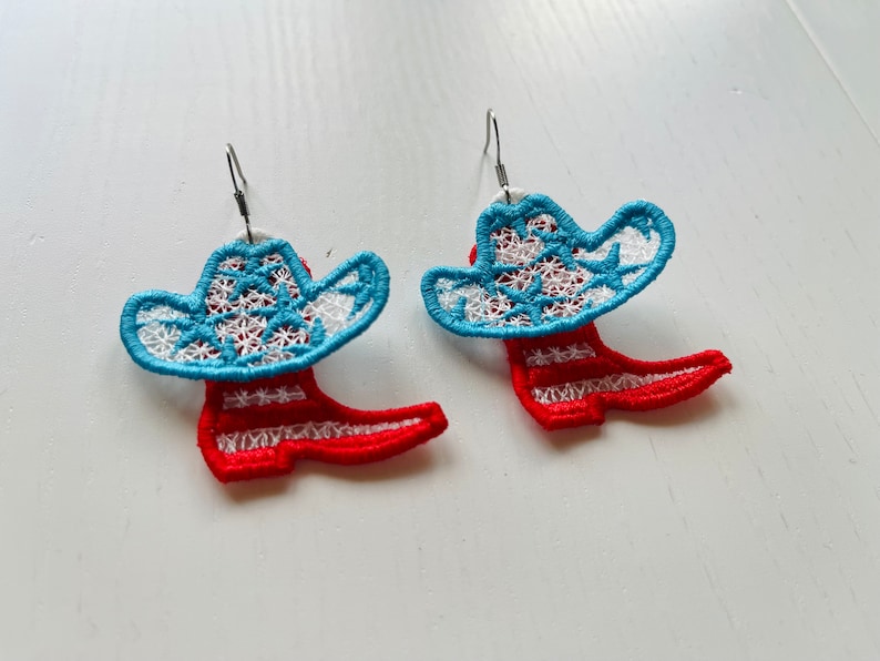 May include: A pair of earrings featuring a red and white striped boot with a blue and white cowboy hat on top.