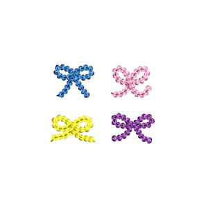 Puede incluir: Cuatro lazos pequeños en diferentes colores: azul, amarillo, rosa y morado. Los lazos están hechos de pequeñas cuentas y están dispuestos en un patrón cuadrado.