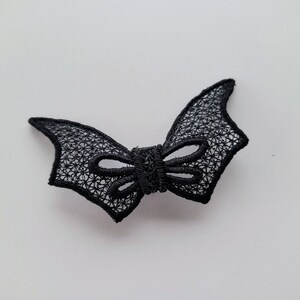 May include: Black lace bow with a bat wing design.