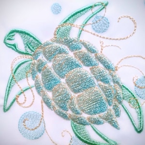 Op de afbeelding: Geborduurde zeeschildpad ontwerp met een blauw en groene schild en gouden accenten. De schildpad is omringd door swirls en bubbels.