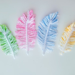 Può includere: Quattro piume di lana colorate con punte bianche. Le piume sono rosa, blu, verde e gialla.