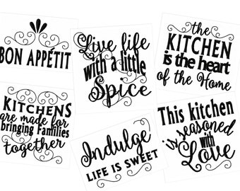 May include: Six black and white kitchen signs with various sayings. The signs read: "Bon Appetit", "Live life with a little spice", "The kitchen is the heart of the home", "Kitchens are made for bringing families together", "Indulge life is sweet", and "This kitchen is seasoned with love".