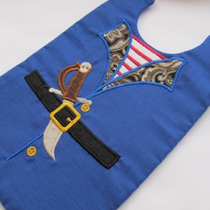 May include: A blue fabric bib with an embroidered design of a pirate costume, including a sword, belt, and shirt collar.