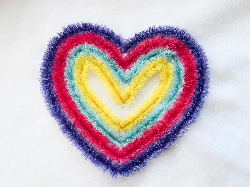 May include: A heart-shaped rainbow made of fuzzy yarn in shades of purple, pink, blue, green, and yellow.