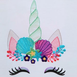 May include: Embroidered design of a unicorn with a green spiral horn, pink ears, and a floral crown with seashells, starfish, and flowers in shades of blue, pink, purple, and green. The unicorn has closed eyes with eyelashes.