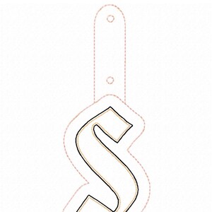 May include: A black and gold embroidered letter S with a white outline. The letter is surrounded by a pink dotted line.