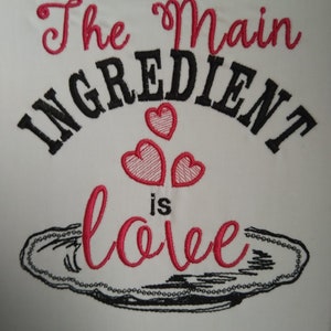 K&ouml;nnte beinhalten: Besticktes K&uuml;chentuch mit dem Text "The main ingredient is love" in schwarzer und rosa Schrift. Drei rosa Herzen befinden sich &uuml;ber dem Text, und eine schwarze Umrandung einer Servierplatte befindet sich unter dem Text.