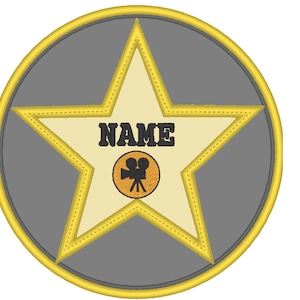 May include: A gold star with a gray background and a film camera icon in the center. The star has a yellow border and the text "NAME" is printed in black.