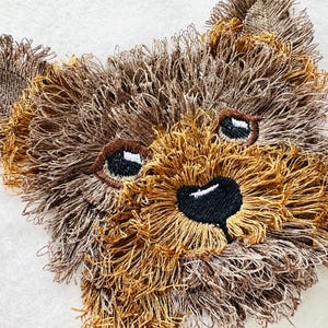 Puede incluir: Primer plano de un rostro de perro Yorkshire Terrier bordado en marr&oacute;n y beige con ojos y nariz negros.