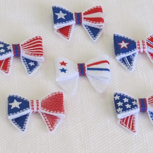 May include: Six red, white, and blue fabric bows with a star pattern. The bows are perfect for adding a patriotic touch to any craft project.