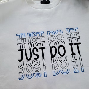 May include: White sweatshirt with a black and blue embroidered design that says "JUST DO IT" multiple times.