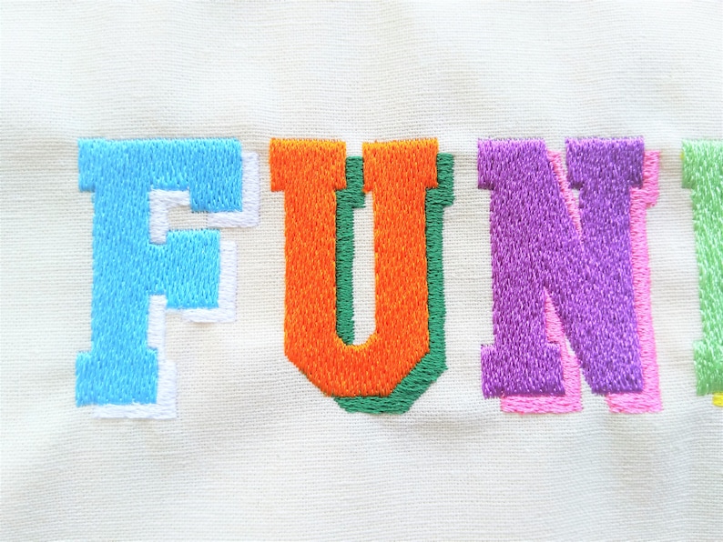 May include: Embroidered word "FUN" in colorful letters. The "F" is light blue with a white outline, the "U" is orange with a green outline, the "N" is purple with a pink outline.