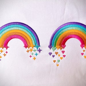 May include: Two embroidered rainbows with different embellishments. One rainbow has stars falling from it, the other has hearts.