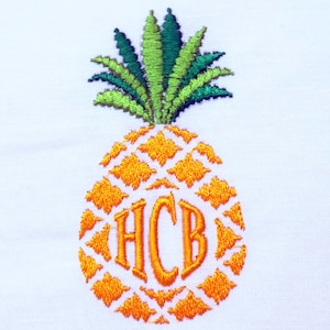 Peut inclure: Broderie d'ananas avec des feuilles vertes et un corps jaune-orange. L'ananas présente les initiales brodées "HCB" dans une couleur jaune-orange assortie. Le motif est sur fond blanc.