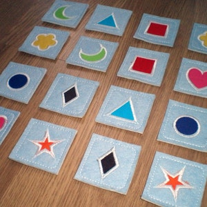 Peut inclure: Un ensemble de 16 carrés en feutre avec différentes formes et couleurs. Les formes comprennent un croissant de lune, un triangle, un carré, une fleur, un cœur, un losange, une étoile et un cercle. Les couleurs comprennent le bleu, le vert, le rouge, le jaune, le rose, le noir, l'orange et le blanc.