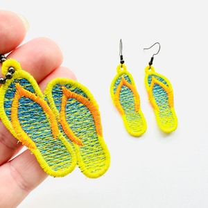 May include: Embroidered jewelry set featuring a pendant and earrings in a flip-flop design. The pendant hangs from a dark chain. The flip-flops are yellow with blue and orange accents, evoking a beach theme.