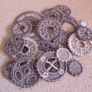 May include: A collection of gray and white lace doilies in various sizes and shapes, resembling gears or cogs. The doilies are arranged in a cluster, creating a decorative and intricate pattern.