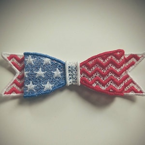 May include: A red, white and blue bow tie with a star pattern on one side and a chevron pattern on the other side.
