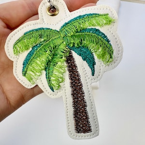 May include: White felt palm tree applique with green and blue embroidered fronds and a brown embroidered trunk.