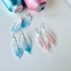 May include: Two pairs of feather earrings. One pair is blue and white ombre, the other is pink and white ombre.