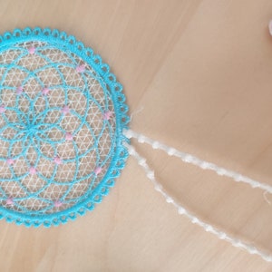 May include: A blue and white dream catcher with pink accents and white beaded strings.