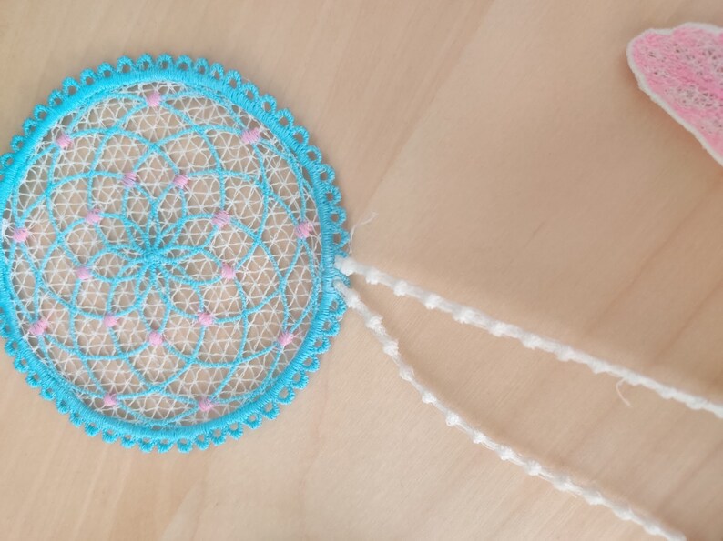 May include: A blue and white dream catcher with pink accents and white beaded strings.