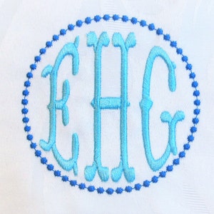 May include: A monogram with the letters EHG in a light blue color, embroidered in a cursive font within a blue dotted oval.