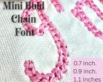 May include: Close-up of a white fabric with pink embroidered chain font letters. The text reads "NEW Mini Bold Chain Font." Measurements are listed in inches: 0.7, 0.9, 1.1, 1.3, 1.5, and 1.9 inches.