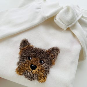 Puede incluir: Sudadera con capucha blanca con un rostro de cachorro Yorkshire Terrier bordado en marr&oacute;n y negro.