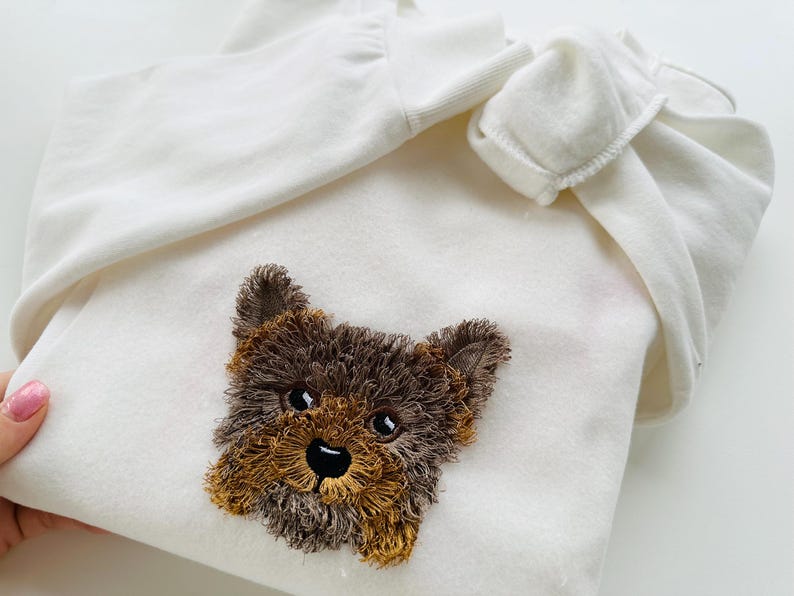 Puede incluir: Sudadera con capucha blanca con un rostro de cachorro Yorkshire Terrier bordado en marr&oacute;n y negro.