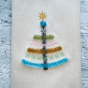 May include: A white fabric Christmas tree ornament with a gold star on top and colorful embroidery details.