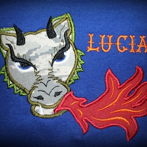 May include: Embroidered gray dragon with green spikes and red flames, breathing fire. The name "LUCIAN" is embroidered in orange above the dragon.