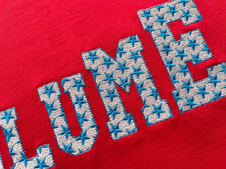May include: Red t-shirt with the word "LUME" embroidered in white with blue star accents.