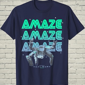May include: Navy blue t-shirt with the word "AMAZE" stacked three times in a gradient of green and blue. A stylized robot figure is below the text, with the words "PROJECT HAILMARY" at the bottom.