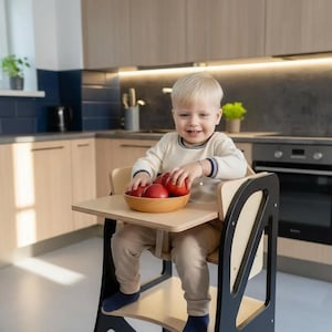May include: A white ceramic mug with a black handle and the text "But First, Coffee" in a bold, black font. The mug is set against a blurred background, suggesting a cozy setting. The mug appears to be approximately 4 inches tall.