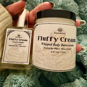 May include: A clear glass perfume bottle and a white jar of whipped body buttercream. Both products are labeled "Fluffy Cream" with the brand name "Beauty By Nari". The perfume bottle is 1 oz, and the jar contains 6.97 oz / 197g of product.