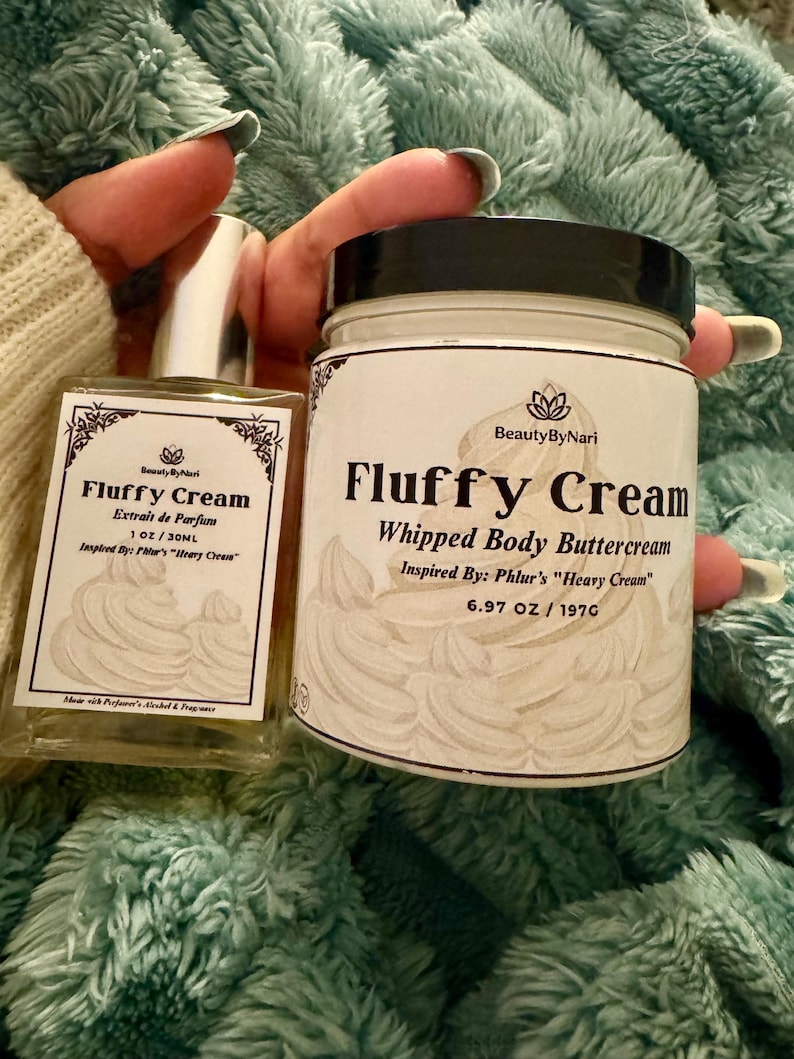 May include: A clear glass perfume bottle and a white jar of whipped body buttercream. Both products are labeled "Fluffy Cream" with the brand name "Beauty By Nari". The perfume bottle is 1 oz, and the jar contains 6.97 oz / 197g of product.
