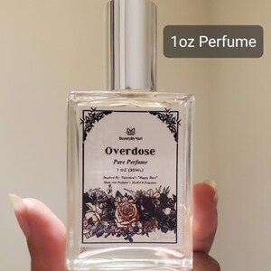 May include: A clear, rectangular perfume bottle with a silver cap. The label reads "Overdose Pure Perfume 1 OZ (30ML)" with floral illustrations. The text "1oz Perfume" is in a gray rectangle.