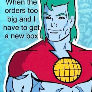 May include: Cartoon image of a superhero with green hair, blue skin, and a red top. The superhero has a yellow globe emblem on the chest. Text reads: "When the orders too big and I have to get a new box."