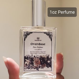 May include: A clear, rectangular perfume bottle with a silver cap. The label reads "Overdose Pure Perfume 1 OZ (30ML)" with floral illustrations. The text "1oz Perfume" is in a gray rectangle.