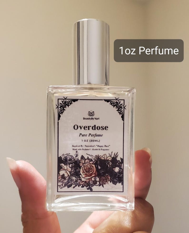 May include: A clear, rectangular perfume bottle with a silver cap. The label reads "Overdose Pure Perfume 1 OZ (30ML)" with floral illustrations. The text "1oz Perfume" is in a gray rectangle.